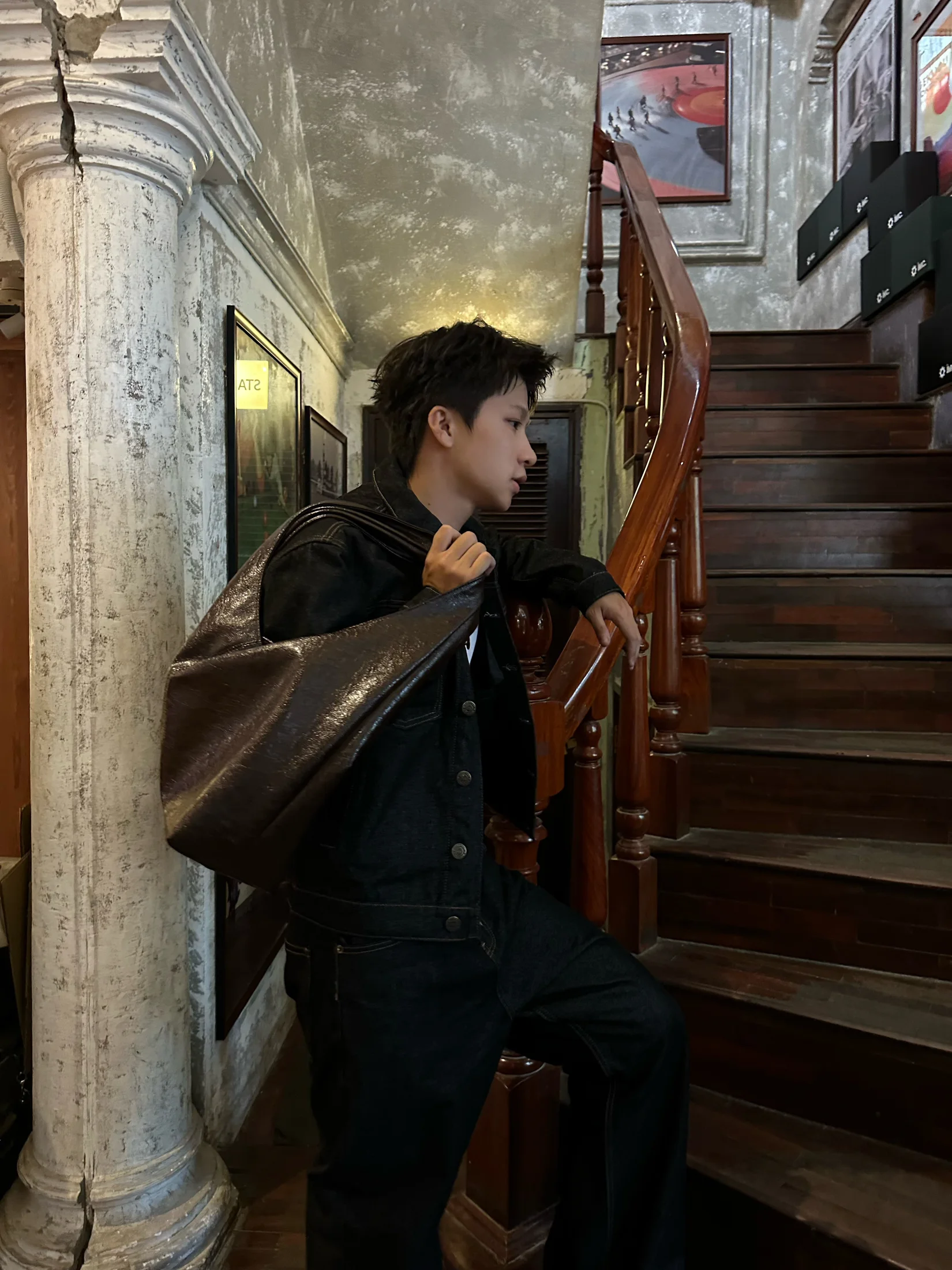Nguyễn Khánh Hưng posing with an oversized leather bag on a staircase