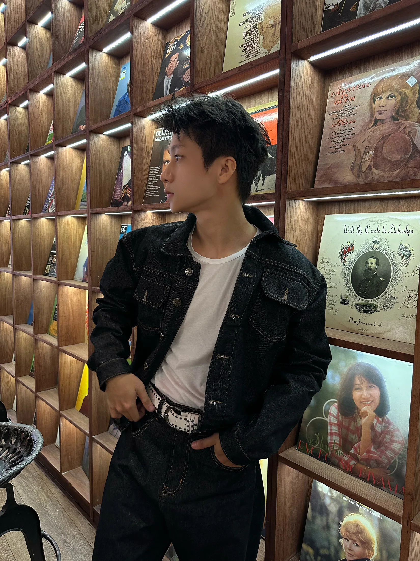 Nguyễn Khánh Hưng adjusting a denim jacket before a large mirror